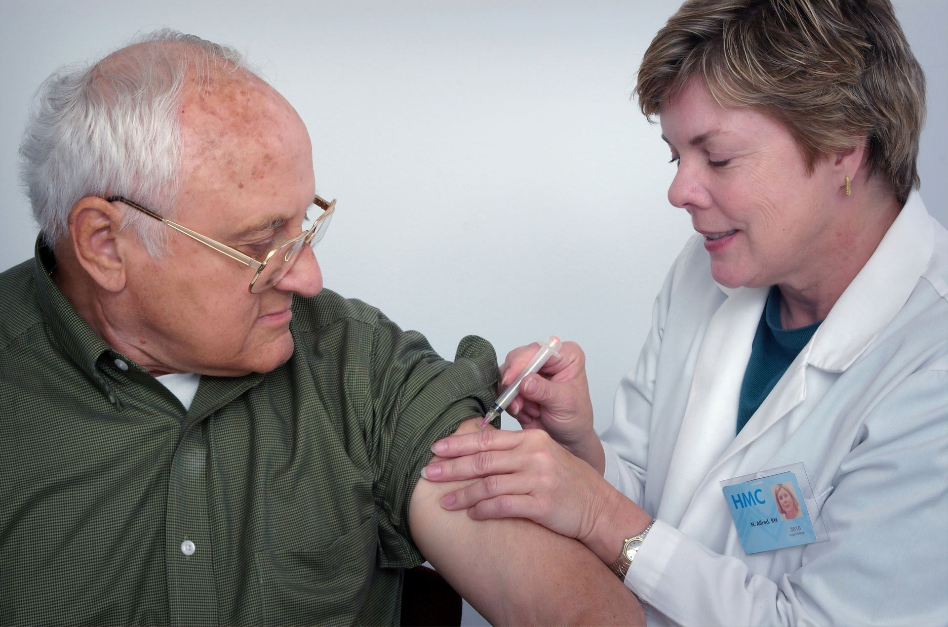 A patient is being vaccinated by a clinician in a white coat